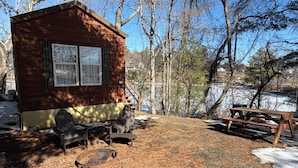 Une cabane en bois avec une terrasse, une table de pique-nique et un foyer.