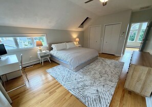 A bedroom with a bed, bedside lamps, a desk, and a window. - 3-bedroom Coastal Narragansett Escape located in the heart of South County (Narragansett)