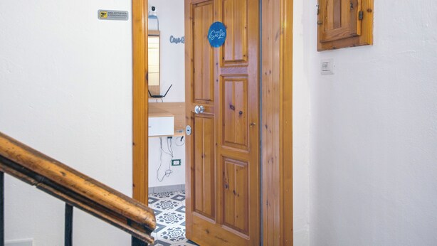 A wooden door with a sign, a tiled floor, and a small cabinet on the wall.