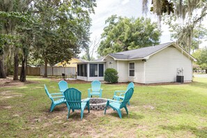 A house with a covered patio area, a small fire pit, and several outdoor chairs. - The Palmetto Blue Cottage Just Minutes to Parris Island! (Port Royal)