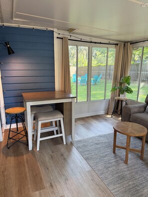 A room with a wooden desk, a stool, a sofa, and a small table.