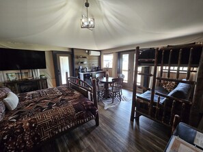Una habitación con cama, una mesa de comedor con sillas, una zona de cocina y una cama elevada con vistas.