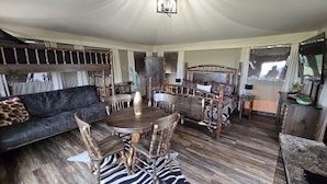 A spacious living area with a round wooden table, a sofa, and a curved wooden bench.