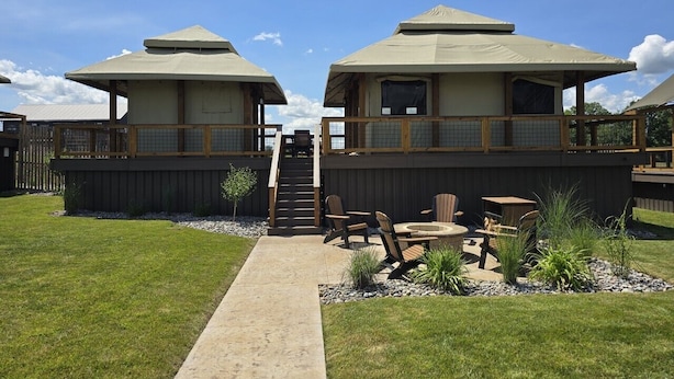 A modern building with two large tents, a wooden deck, and outdoor seating.