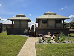 A modern building with two large tents, a wooden deck, and outdoor seating.