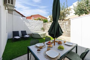 Un patio con mesa lista para el desayuno, sillas, un jacuzzi y un muro de piedra.
