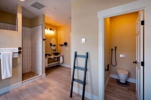 A bathroom with a shower, toilet, and a sink with a mirror. - Vinifera Suite at The Barn | Boutique Hotel (Walla Walla)
