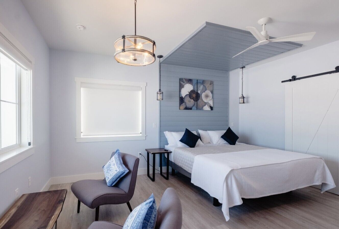 Un dormitorio moderno con cama, sillón, escritorio y ventilador de techo.