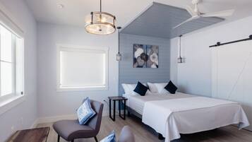 Un dormitorio moderno con cama, sillón, escritorio y ventilador de techo.