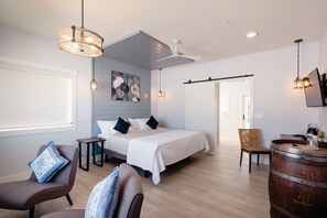 A modern hotel room with a bed, seating area, and a bar.