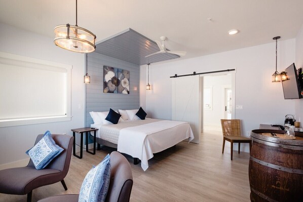 A modern hotel room with a bed, seating area, and a bar. - Vinifera Suite at The Barn | Boutique Hotel (Walla Walla)