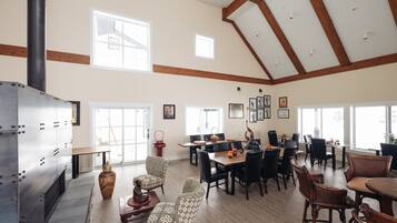 Un comedor amplio con techos altos y ventanas grandes, con una combinación de mobiliario moderno y tradicional.