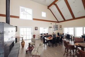 A spacious dining area with high ceilings and large windows, featuring a mix of modern and traditional furniture. - Vinifera Suite at The Barn | Boutique Hotel (Walla Walla)