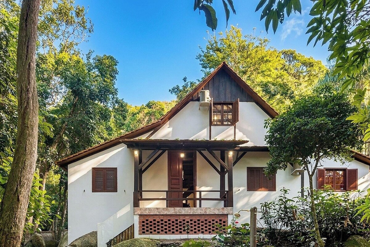 A two-story house with a gabled roof, wooden shutters, and a balcony.