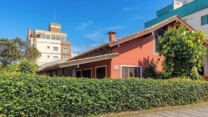 A residential building with a red facade, a tiled roof, and a well-maintained hedge in the foreground. - House With Private Pool Near the Beach Rox0325 (Bombinhas)