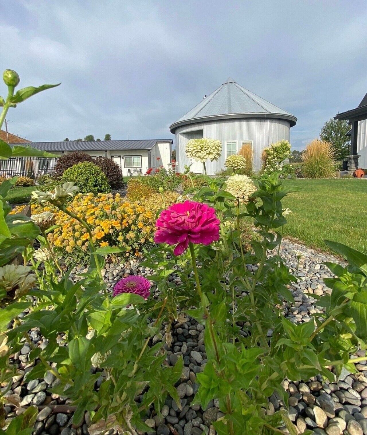 A garden with a variety of flowers and a building with a circular roof.