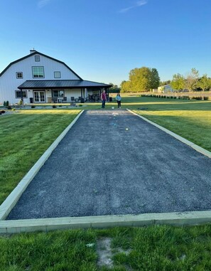 A courtyard with a croquet field, a white building, and a lawn.