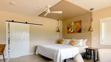 Un dormitorio con cama, ventilador de techo, un cuadro y ventana.