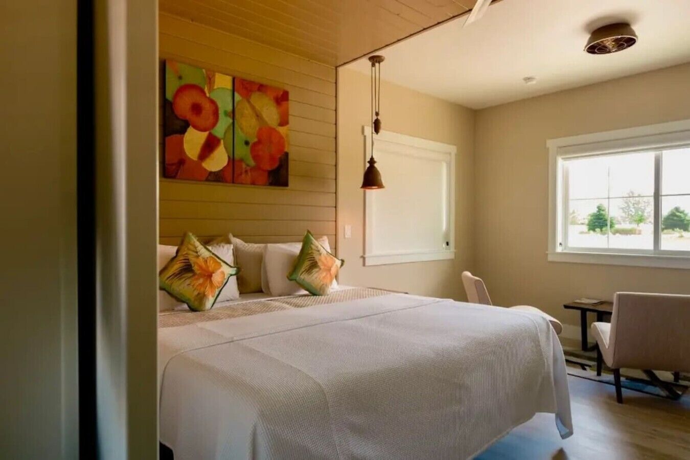 Habitación de hotel con una cama grande, un cuadro en la pared, una ventana con vistas y una silla.