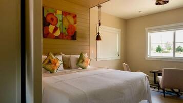 Habitación de hotel con una cama grande, un cuadro en la pared, una ventana con vistas y una silla.
