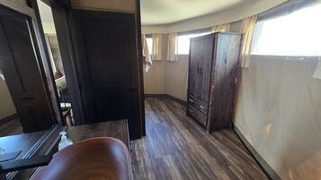 Una habitación con piso de madera, un mueble oscuro de madera y una puerta que da a otra estancia.