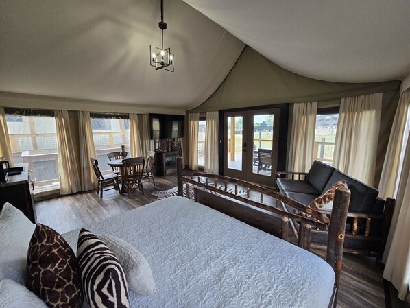 A spacious bedroom with a large bed, a dining area, and a view of the outdoors.