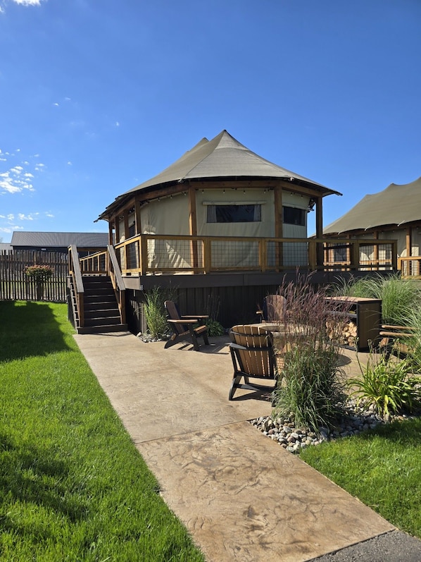 A two-story building with a covered patio area, outdoor seating, and a wooden fence.