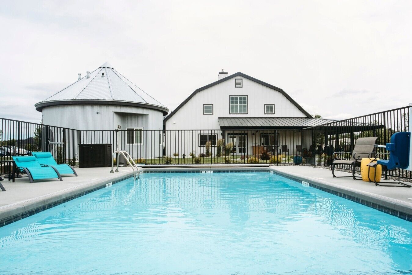 Una piscina con sillas de descanso y un área cercada.