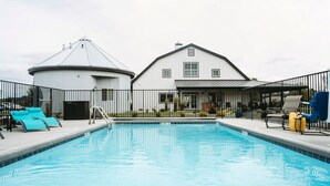 Piscina com espreguiçadeiras e área cercada.