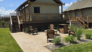 A two-story building with a covered patio area, outdoor seating, and a staircase leading to an upper deck.