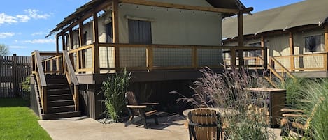 Ein zweistöckiges Gebäude mit einer überdachten Terrasse, Sitzgelegenheiten im Freien und einer Holzterrasse.
