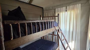 Un lit superposé avec une échelle, un matelas bleu foncé et une tête de lit en bois.