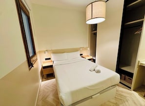 Ein Hotelzimmer mit Bett, Nachttischen, einer Lampe und einem Kleiderschrank.