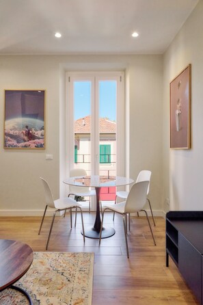 A dining area with a round table and four chairs, a sofa, a framed picture, and a view through a glass door. - Casa e Appartamento Vacanze Gallese 12 (Roma)