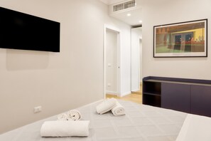 Habitación de hotel con cama, televisor de pantalla plana montado en la pared y un cuadro enmarcado sobre la cama.