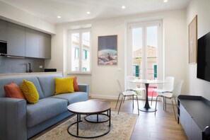 Una sala de estar moderna con sofá, mesa de centro y sillones. Hay un televisor de pantalla plana montado en la pared.