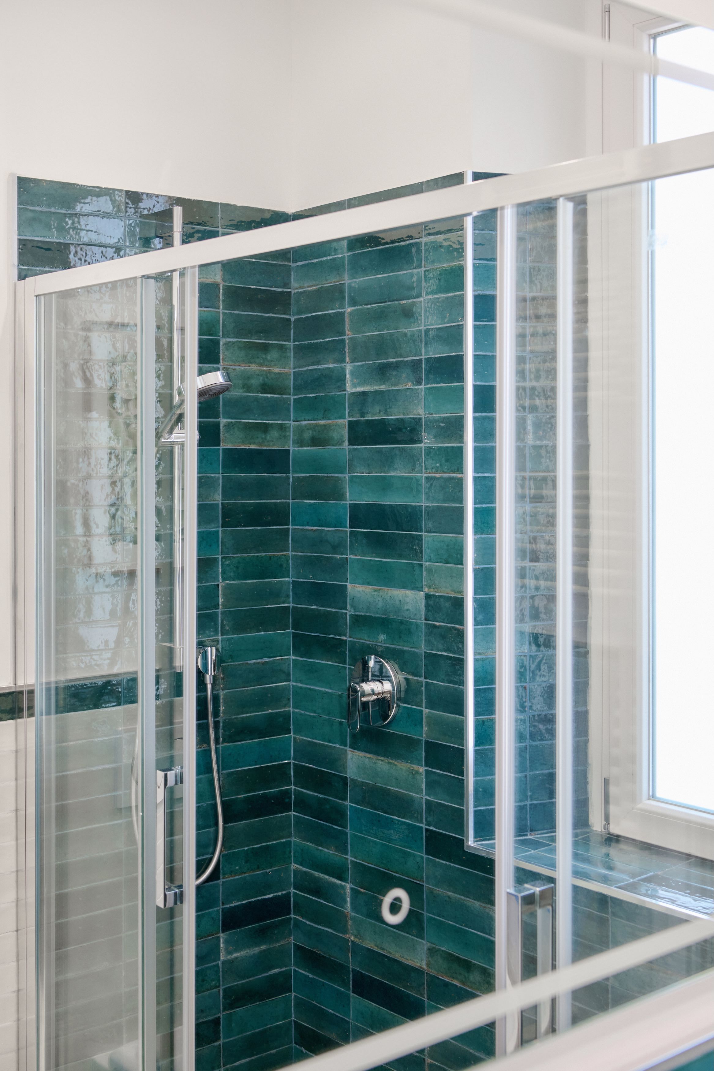 A glass-enclosed shower with a tiled wall.