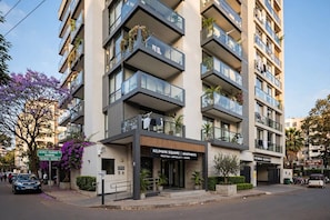 A modern apartment building with balconies, a reception area, and a sign indicating parking. - Cozy Air BNB 2BR-Fast WiFi (Nairobi)