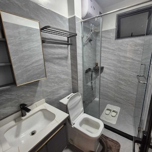 A modern bathroom with a glass-enclosed shower, a white sink, and a toilet. - Cozy Air BNB 2BR-Fast WiFi (Nairobi)