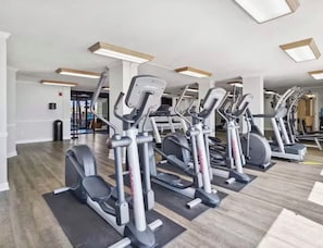 A gym with multiple treadmills aligned in rows, equipped with mats, and overhead lighting. - Spacious 3-bedroom BEACHFRONT condo in Panama City Beach (Panama City Beach)