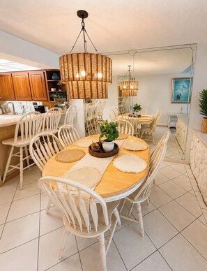 A dining area with a round wooden table, white chairs, and woven pendant lights. - Spacious 3-bedroom BEACHFRONT condo in Panama City Beach (Panama City Beach)