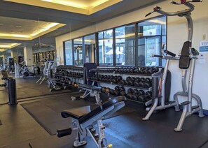 Une salle de sport équipée de divers appareils d’exercice, notamment des haltères, des tapis de course et des appareils de musculation.