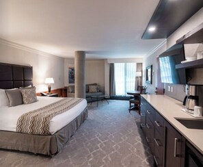 Une chambre d’hôtel avec un grand lit, un bureau, un canapé et une kitchenette.