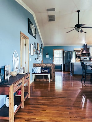 A spacious kitchen with a wooden bench, a ceiling fan, and a refrigerator.