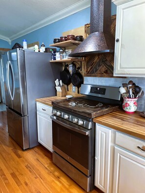 A kitchen with stainless steel appliances, wooden countertops, and a variety of utensils and cookware.