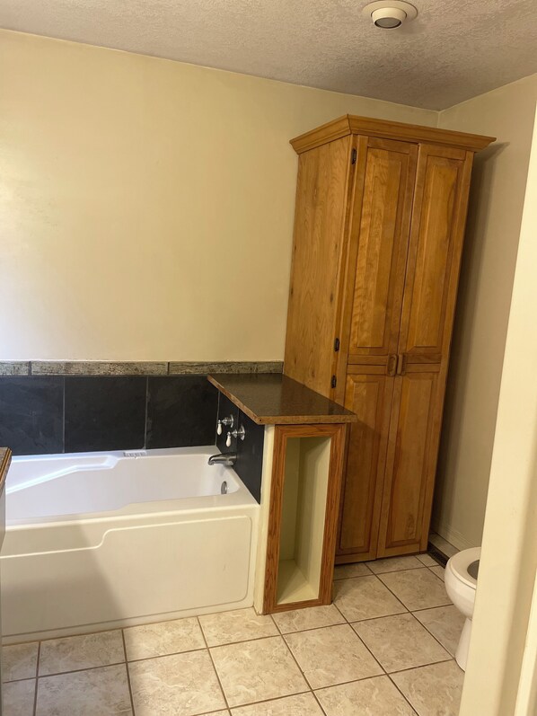 A bathroom with a white bathtub, a wooden cabinet, and a toilet.