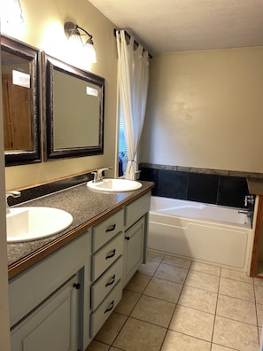 Une salle de bain avec deux lavabos, une baignoire et un miroir avec éclairage.