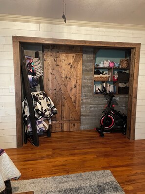 A room with a wooden door, a shelf with various items, and an exercise bike.