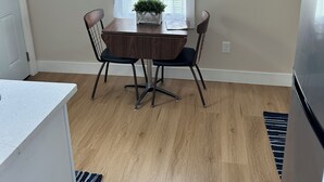 Cozinha com mesa de jantar, cadeiras, geladeira e janela com persianas.
