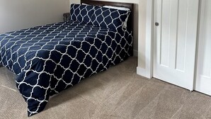 Quarto com cama, ar condicionado, porta e quadro na parede.